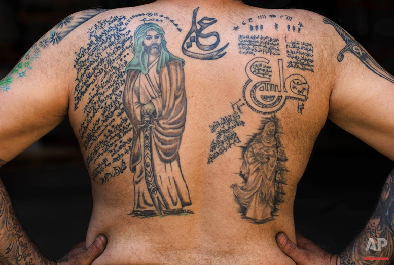 In this Tuesday, May 10, 2016 photo, Ali Hussein Nasreddine, 50, poses for a photo showing off his tattoos of Shiite Muslim religious slogans and Shiite Muslims' first Imam Ali, in the southern suburb of Beirut. (AP Photo/Hassan Ammar)